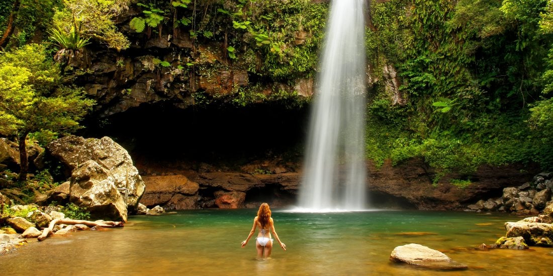 Young woman in bikini standing by Lower Tavoro Waterfalls in Bouma National Heritage Park, Taveuni Island, Fiji
